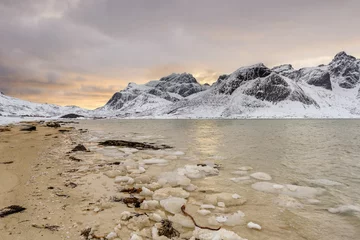 Poster Lofoten Islands in Norway and their beautiful winter scenery at sunset. Idyllic landscape on snow covered beach. Tourist attraction in the arctic circle. Nordic travel destination. © aroxopt