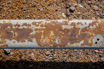 A metal rusty pole lies on the ground