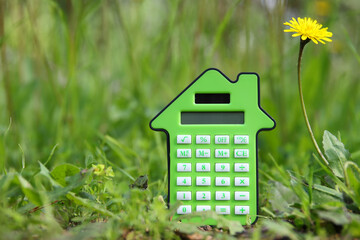 Calculator in the shape of a house in nature. Idea of expenses and real estate