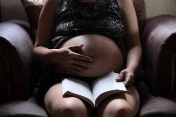 mujer embarazada leyendo. - obrazy, fototapety, plakaty