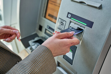 Hand inserting a credit card into an ATM slot, banking in action with a focus on security and...