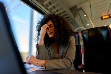 Young lady experiencing a headache from work fatigue on her train journey, needing a break.