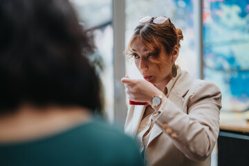 A focused businesswoman converses with a colleague in a well-lit office setting, exemplifying...