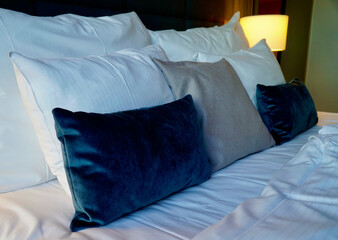 Luxurious hotel room bed with crisp white linen and elegant blue pillows.