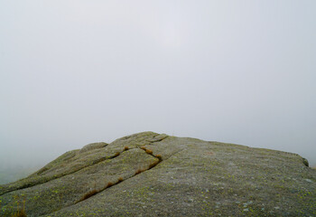 Eerie view of a cliff emerging from dense clouds, creating a mystical atmosphere.