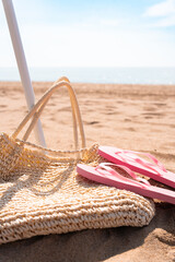 Close up of beach bag with flip flops and umbrella stick on a beautiful summer morning on the...