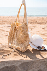 Summer vacation concept. Beach bag with hat, sunglasses next to umbrella on a beautiful bright...
