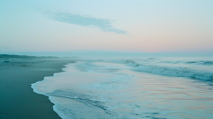 A scenic view of the ocean waves gently breaking on a quiet beach as a pastel sky stretches above early in the morning
