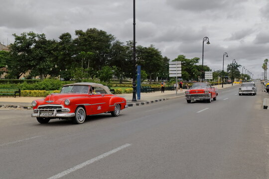 INCIDENTAL, NON RECOGNIZABLE PEOPLE IN THE IMAGE. Red Chevrolets from 1952-56 and gray Buick from 1958 American classic cars -almendron, yank tank- on Avenida del Puerto-Port Avenue. Havana-Cuba-063