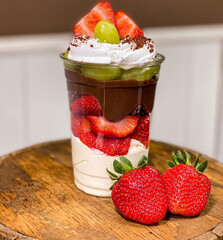 Delicious white chocolate mousse with strawberries and green grapes in a jar for delivery
