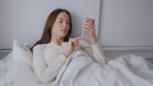 Young Woman Using Smartphone in Bed Comfortably