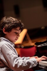 Fototapeta na wymiar Young Boy Performing Piano in Front of Crowd