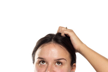 half portrait of a young woman looking up and sctratching her head on a white background