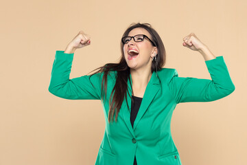 Businesswoman in green suit showing biceps on a beige background