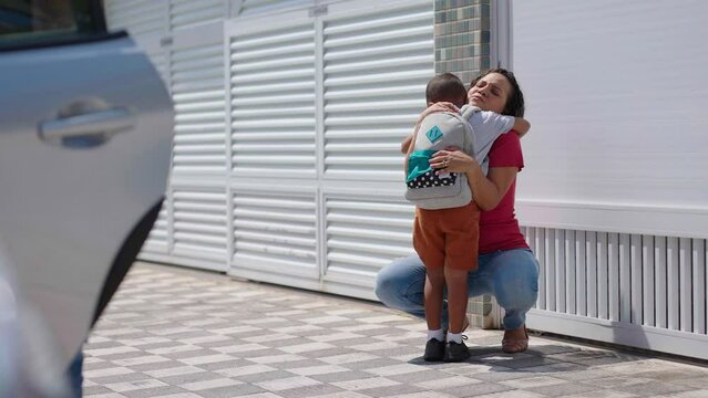 Hard-working, ambitious mother picking up son from school, greeting him. Concept of work-life balance for women.
