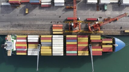Top down aerial view of cargo ship loading containers. Showcases maritime shipping efficiency. Part of global distribution network.
