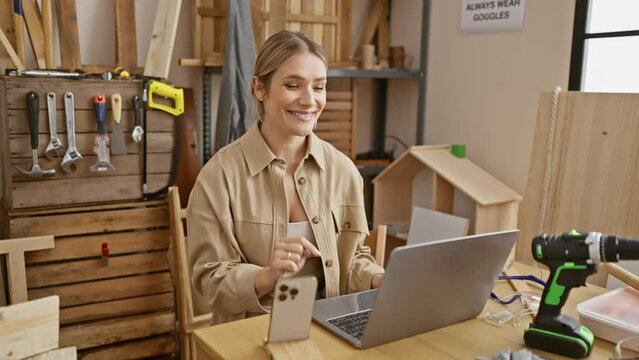 Blonde bombshell carpenter, number one in her trade, surprised with a brilliant idea while surfing her laptop, pointing with a confident smile and cheerful face