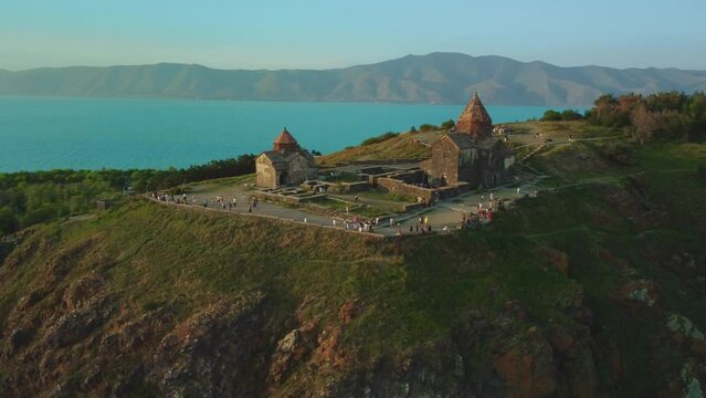 Shot of Sevanavank church on a peninsula with Lake Sevan and hills in the background.