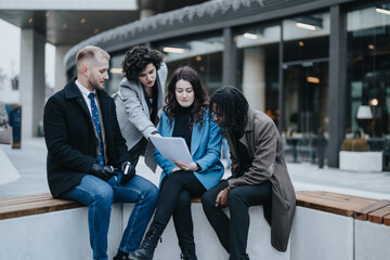 Four international business teammates engage in a collaborative discussion over documents, displaying teamwork in an urban outdoor environment.