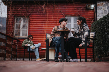 Obraz premium Young couple sharing a moment with hot beverages on a rustic cabin's front porch, exuding warmth and happiness.