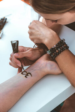 Mehendi master drawing henna tattoo on female hand,mehendi art