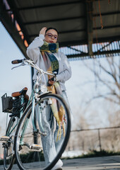 Stylish young woman with classic bicycle on an urban bridge in autumn.