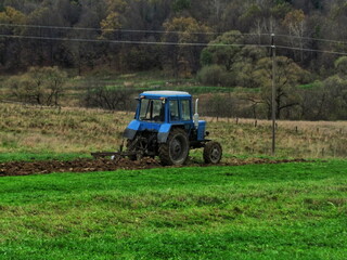 Mechanized plowing of land with the help of a tractor in autumn