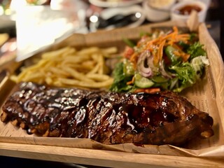Barbecue Grilled Pork Ribs with French Fries and Salad on Wooden Plate in a restaurant