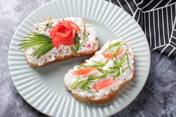 Bruschetta, a slice of bread with cheese paste, tomato and cucumber. Beautifully decorated sandwiches on a plate