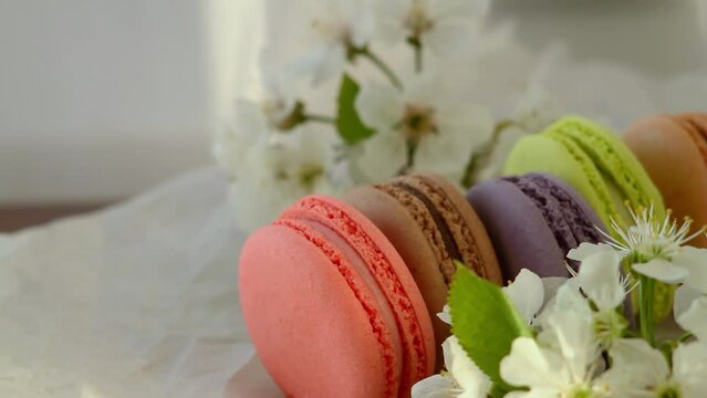 brown macaroons of red, brown purple, green and beige spins on white paper with apple blossoms