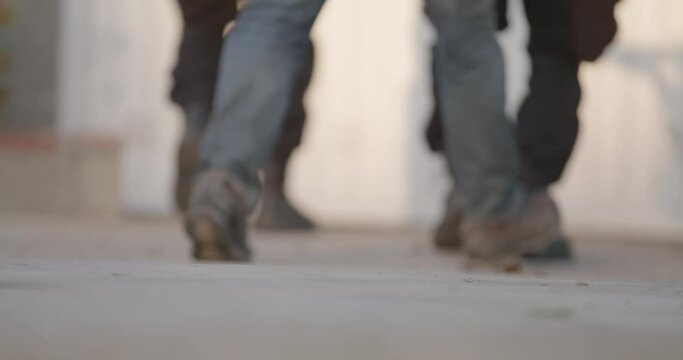 Swat, military, or black military boots moving in coordination. Preparing for raid. Walking on concrete, Low angle of feet. High intensity movement. concrete, Low angle of feet. Daytime