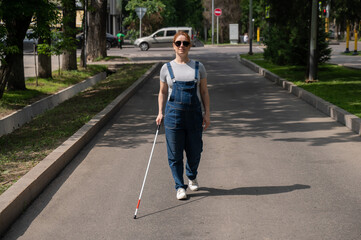 Blind pregnant woman walking down the street with a cane. 
