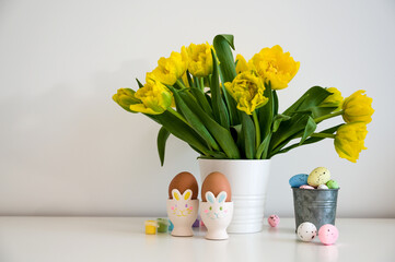 Easter greeting card with bunch of yellow tulips,eggs in bunny holders in pastel colors