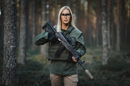 Beautiful military girl with a modern AK 12 rifle in the forest at war.