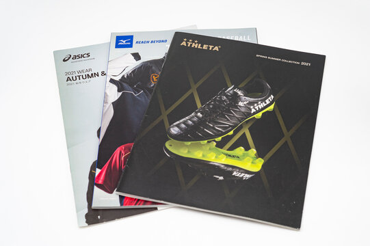Fuji city, Shizuoka-ken, Japan - January 1, 2023: Advertising catalogs for footwear and sportswear from the brands Athleta, Mizuno and Asics isolated on white background
