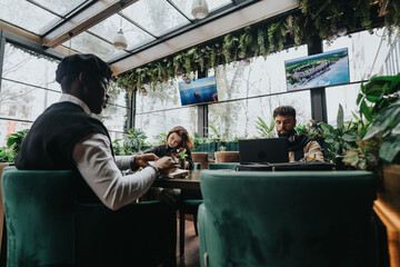 Young entrepreneurs collaborating in stylish urban coffee shop with greenery.