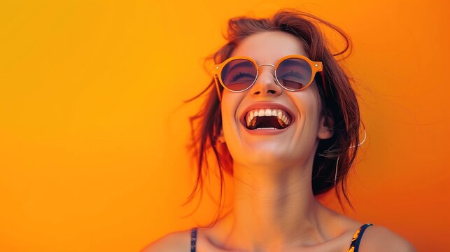 A joyful young woman wearing sunglasses, laughing and enjoying the sunshine, against a vivid orange background, real photo, stock photography  generative ai