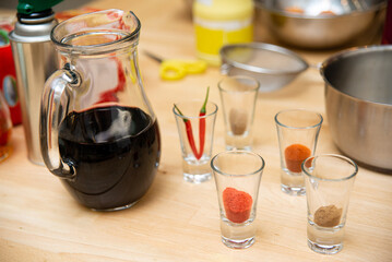 Cooking Spices and Soy Sauce Preparation. Assorted spices measured in shot glasses and a pitcher of soy sauce, set up for cooking a flavorful recipe.