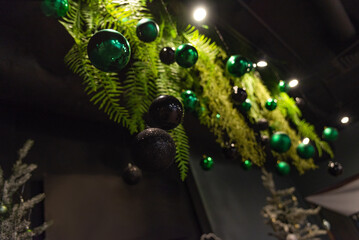 Christmas Decorations with Green and Black Ornaments. Elegant Christmas decorations featuring a mix of shiny green and black ornaments hanging amongst vibrant green ferns, creating  festive atmosphere