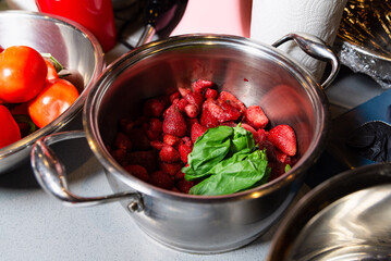 Fresh Strawberries and Basil in a Kitchen Bowl. A stainless steel bowl filled with bright red strawberries and fresh basil leaves on a kitchen countertop. - Powered by Adobe