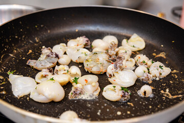 Sautéed Mixed Seafood in a Frying Pan. Fresh variety of seafood including squid and cuttlefish being sautéed with herbs and spices in a non-stick pan, a delicious meal preparation.
