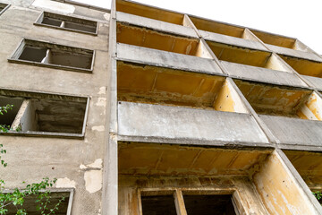 Fototapeta na wymiar Abandoned Prefabricated Building Overgrown and missing windows