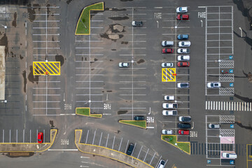 Aerial view of expansive parking lot with cars parked, empty spaces, and designated spots for...