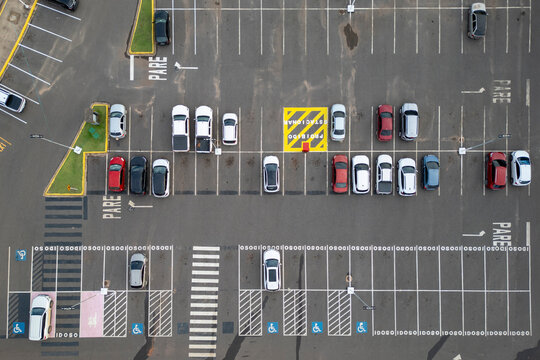 Aerial view of expansive parking lot with cars parked, empty spaces, and designated spots for disabled and elderly individuals.