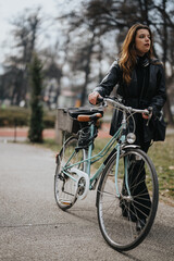 An active businesswoman walking alongside her bicycle in an urban park, depicting eco-friendly commuting.