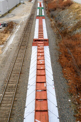 Looking down from a bridge at a long line of cars in a freight train.