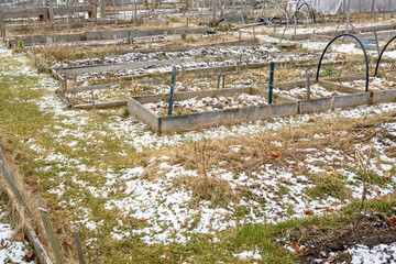 A community garden in winter. The garden has places for plants, but is otherwise empty except for dead grass and snow.
