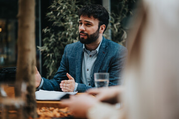 A focused male business entrepreneur engaged in a discussion during a casual work meeting in an outdoor setting