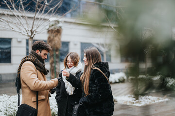 A group of young people bundled up against the cold share a conversation and laughter on a snowy day outdoors.