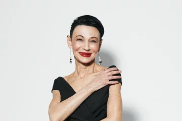 Foto op Aluminium Elegant older woman in black dress and red lipstick posing in front of white wall © SHOTPRIME STUDIO